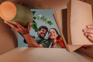 Happy couple unpacking cardboard box in new home