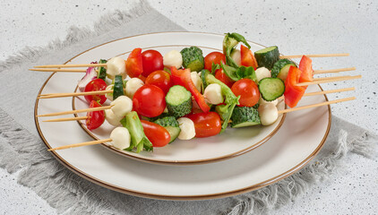 Appetizer of fresh vegetables and cheese on wooden skewers in a plate on the table