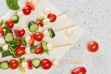 Italian appetizer with cherry tomatoes, cucumbers and mozzarella on a white board