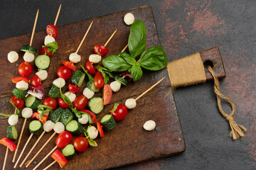 Italian appetizer with cherry tomatoes, cucumbers and mozzarella on a wooden board