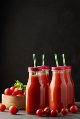 Full glass bottle with tomato juice on dark background