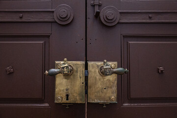 Fototapeta premium Two metal old door handles on brown wooden doors.