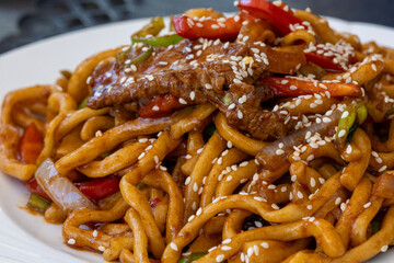 Traditional Uighur Laghman Noodles with Vegetables and Meat on a Rustic Table