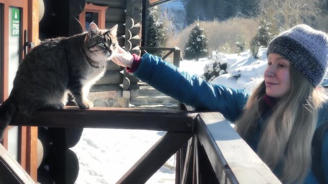 Girl strokes the rural cat on porch of house in Carpathians. Ukraine.