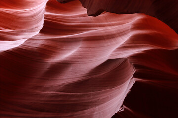 A red wall resembling sea waves. Rays of light are breaking through from above