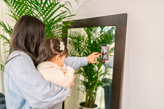 Mother and daughter making a video call with smartphone at home