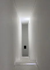 Fotobehang Gang Minimalist interior staircase with white walls and subtle lighting creating a tunnel-like  © valiantsin