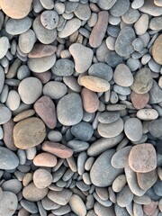 Close-up texture of natural sea stones on Moncofa beach, showing smooth and rough surfaces in earthy tones.