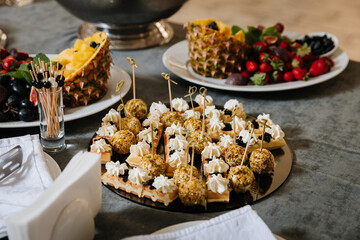 Elegant catering plate with waffle canapes, cheese balls, and exotic fruit on table