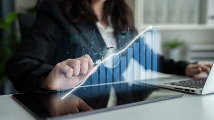 A business professional analyzes financial data on a tablet, featuring a digital graph overlay. This image captures modern technology in a corporate setting. Impute