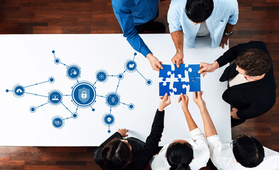 A top-down view of a diverse team collaborating on a network security strategy, using puzzle pieces and digital icons to represent crucial elements of cybersecurity solutions. Amity