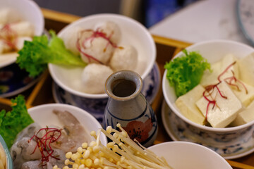 Asian restaurant menu on the tabel featuring hot pot broths, ramen, seafood, meats, vegetables, and tofu.