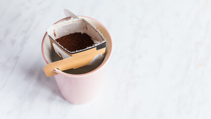 Drip bag in a ceramic cup on windowsill. Instant freshly brewed alternative filter drink in mug....