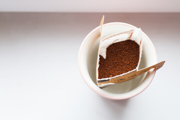 Drip bag in a ceramic cup on windowsill. Instant freshly brewed alternative filter drink in mug. Easy brew black coffee method for home, travel or office. cozy trendy lifestyle