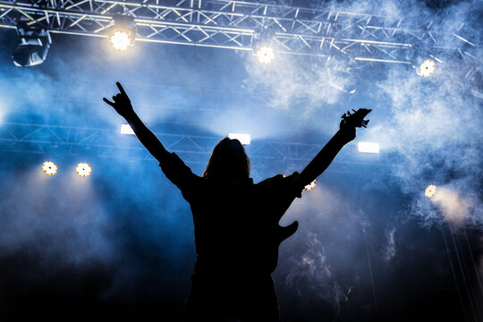 silhouette of man or Rockstar wit Guitar with arms raised