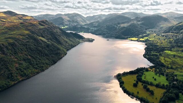 aerial drone shot flying down ullswater lake in mountain hill valley with mountains in background at sunset in summer in England lake district - Powered by Adobe