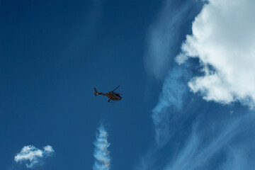 Single aerobatic helicopter releasing smoke in blue sky.