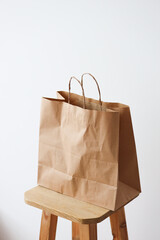 Brown paper bag on wooden stool against white background