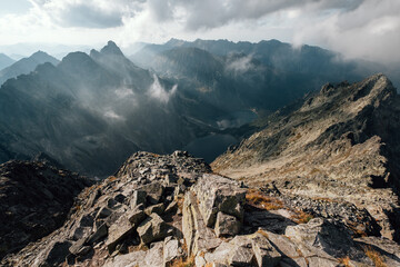 Misty clouds rising up over Morskie Oko lake early morning in High Tatras mountain range with incredible light and shadows play. Rysy peak 2499m view. Lake Morskie Oko is visible below. © Soloviova Liudmyla