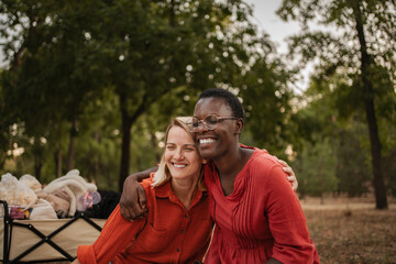Two smiling friends hugging at the park