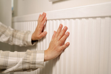 Woman warming up hands over heater. Increasing bills expenses. Cold season. Rising utility costs