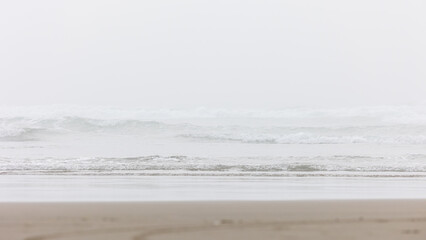 Gentle waves roll onto the sandy stretches of Oregon’s foggy shoreline