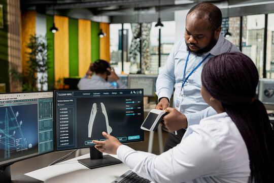 Green technology company engineering team working on innovative sustainability projects in office, integrating solar energy products with advanced electric grid solutions.