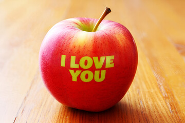 Red apple with green text message on wooden surface image