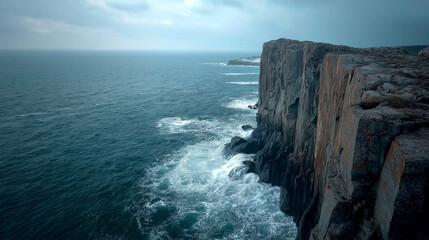 A rugged rocky cliff edge overlooked the expansive ocean under a golden sunset, with waves crashing powerfully against the shore below.