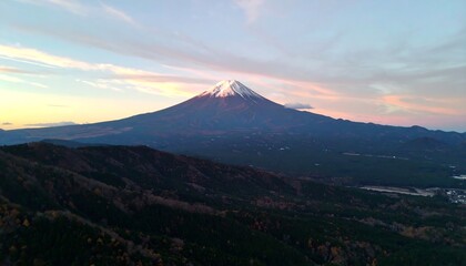 Naklejka premium A breathtaking vista showcasing Mount Fuji at dawn, with layers of hills and forests cascading down to the valley.