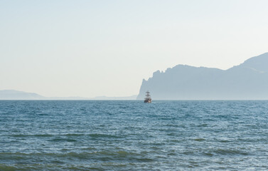 Historic sailing ship at sea near mountain foothills