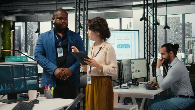 Diverse workers team use digital tools and analytics to improve growth strategy, reviewing financial insights on tablet to foster innovation and development in a modern office environment.