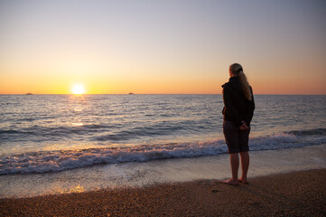 A woman stands on the seashore