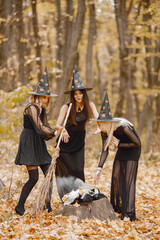 Three witches in forest on Halloween make magic potion