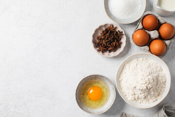 Baking ingredients flat lay with flour, eggs, sugar, and spices on marble surface. Copy space