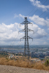 A high-voltage power line tower is the central element in this landscape, with the urban area of Viladecans, industrial buildings, and fields visible below.