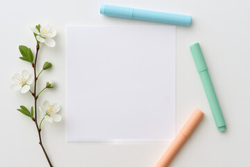 Minimalist self-care concept with blank paper, blossoms, and pastel markers on white background for relaxation, creativity, and mindfulness activities