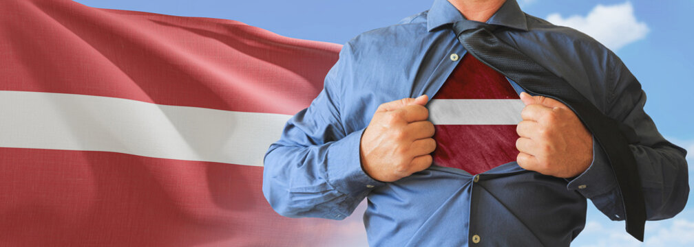 A businessman opening his shirt like super hero with Latvia flag and shows how patriotic he is by revealing his countries flag beneath printed on a t-shirt.