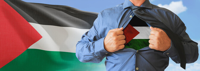 A businessman opening his shirt like super hero with Palestine flag and shows how patriotic he is by revealing his countries flag beneath printed on a t-shirt.