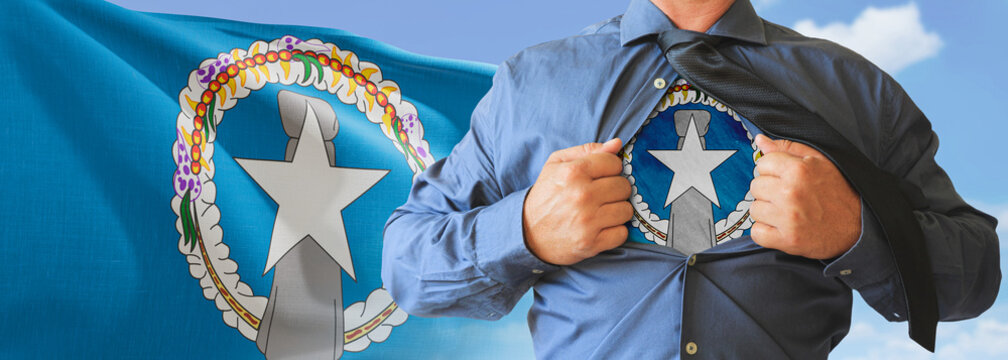 A businessman opening his shirt like super hero with Northern Mariana Islands flag and shows how patriotic he is by revealing his countries flag beneath printed on a t-shirt.