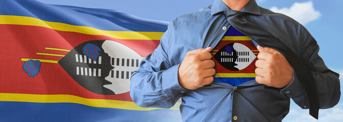 A businessman opening his shirt like super hero with Swaziland flag and shows how patriotic he is by revealing his countries flag beneath printed on a t-shirt.