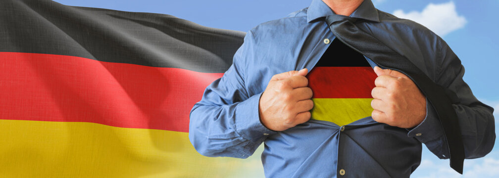 A businessman opening his shirt like super hero with Germany flag and shows how patriotic he is by revealing his countries flag beneath printed on a t-shirt.