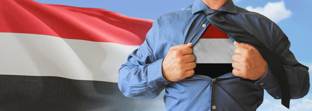 A businessman opening his shirt like super hero with Yemen flag and shows how patriotic he is by revealing his countries flag beneath printed on a t-shirt.
