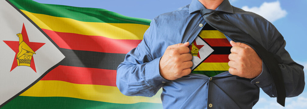 A businessman opening his shirt like super hero with Zimbabwe flag and shows how patriotic he is by revealing his countries flag beneath printed on a t-shirt.