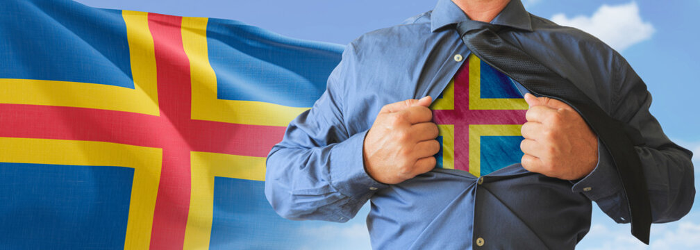 A businessman opening his shirt like super hero with Aland Islands flag and shows how patriotic he is by revealing his countries flag beneath printed on a t-shirt.