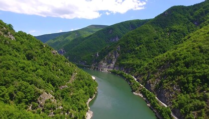 A high-angle view of a river winding through lush green mountains.