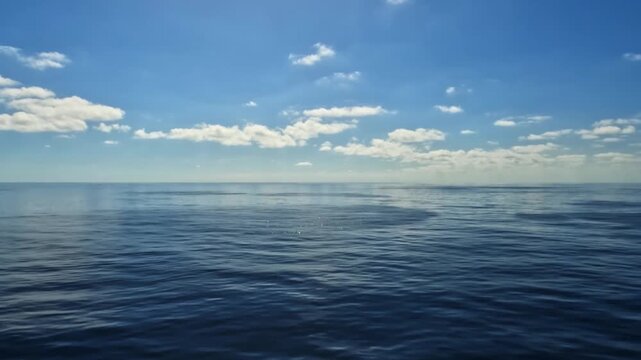 White clouds in blue sky and ocean with calm waters. Sailboat traveling in open sea during vacation. Cruise ship sailing