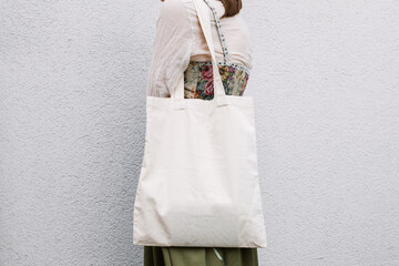 Young white woman holding black eco bag on arm shoulder or hand, street wall at background. city...