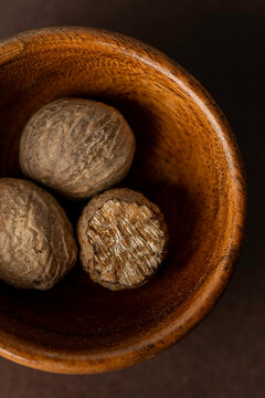 Closeup of whole nutmeg in a small wood bowl 