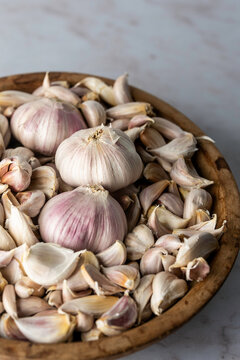 Bulb of garlic sitting in cloves of garlic in a wood bowl
